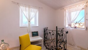 A room with a yellow chair, a white desk, a black metal partition, and a window with white curtains. - Nina's Traditional House by Estia (Corfu)