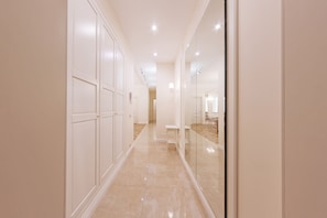 Stylish corridors lead to rooms and suites, with a dining area visible through a large mirror.