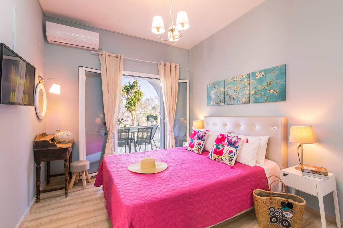 Ein Schlafzimmer mit Bett, Nachttisch und Blick durch ein Fenster.