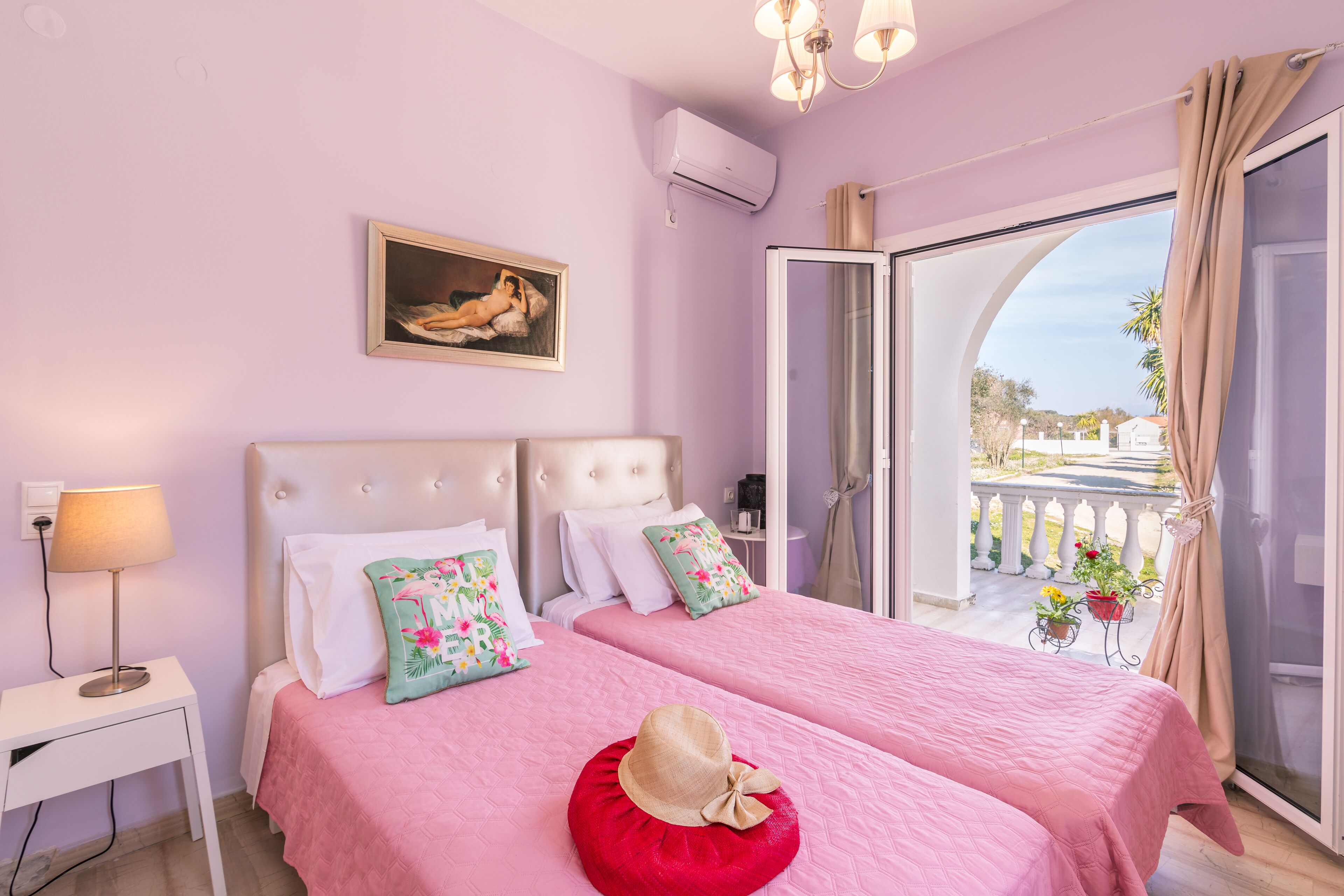 Un dormitorio con dos camas, un cuadro en la pared y vistas al balcón exterior.