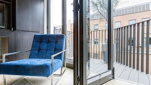 A blue chair in a room with a glass door leading to a balcony. - Goodge Street IV (London)