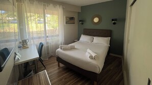 Een hotelkamer met een bed, een bureau en een raam met gordijnen.