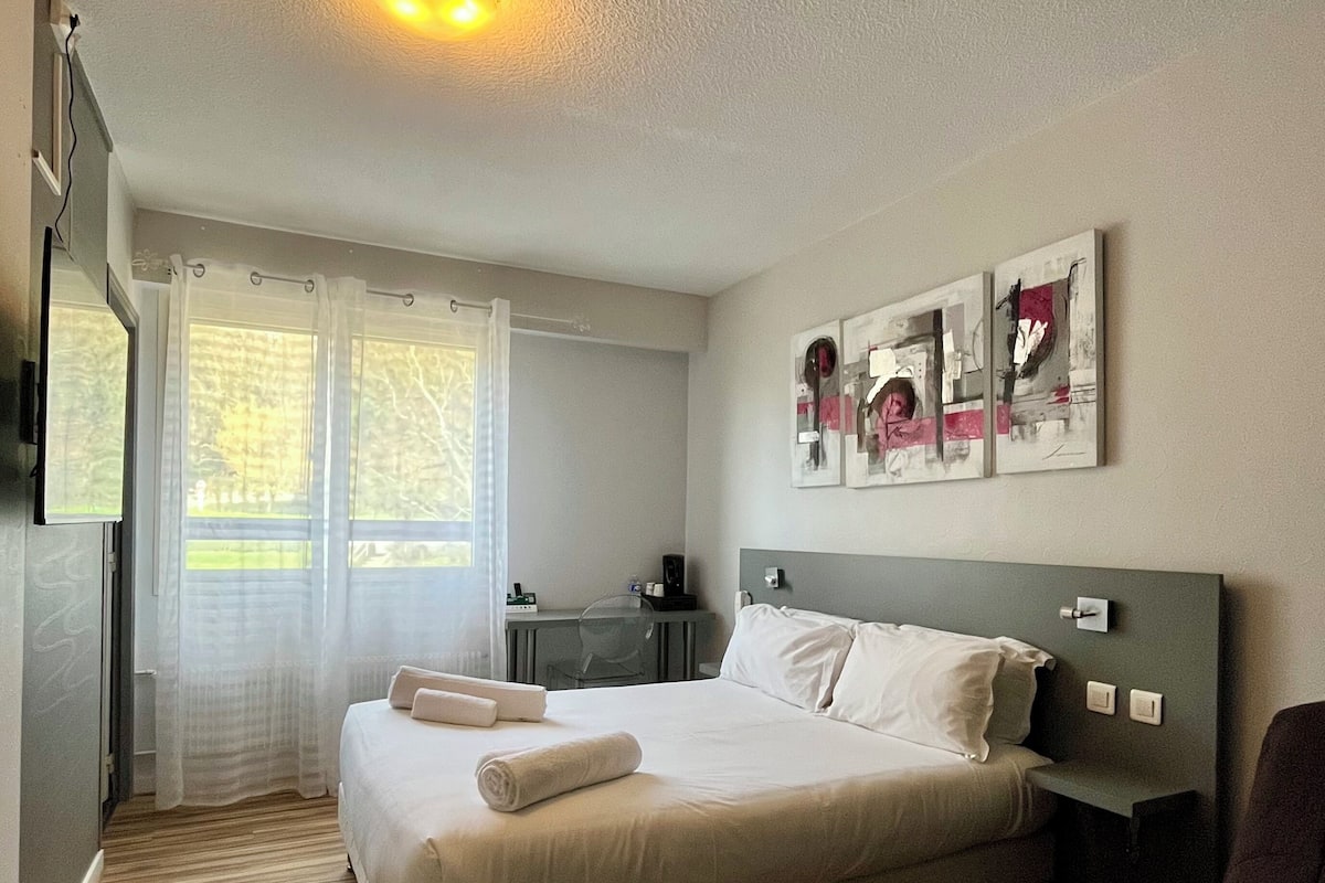 Una habitación de hotel con cama, escritorio, silla y cuadros en la pared.