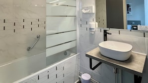 Een moderne badkamer met een douchecabine van glas, een witte wastafel en een spiegel erboven.