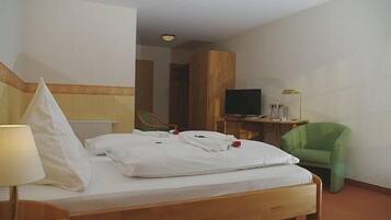 Ein Hotelzimmer mit einem Bett, einem Fernseher, einem Schreibtisch und einem grünen Sessel.