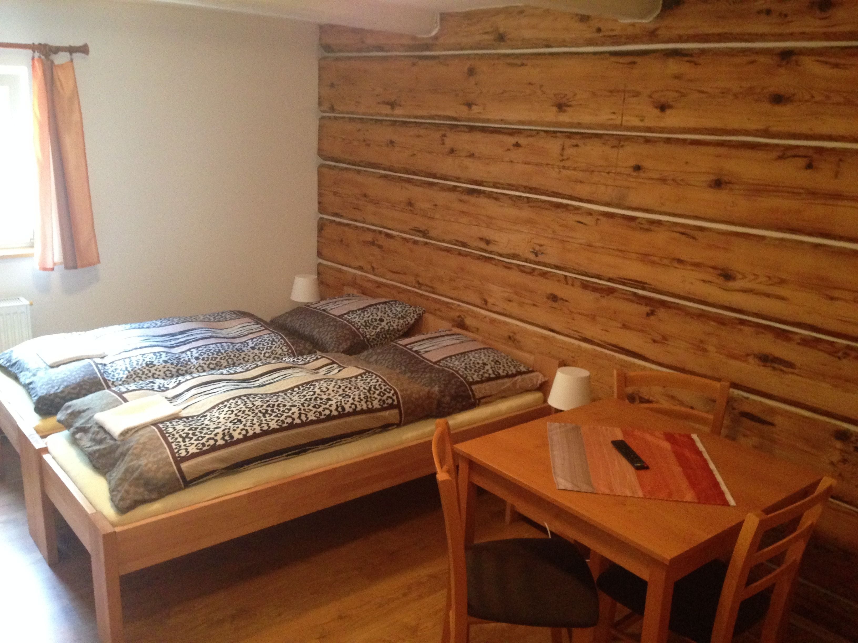 Une chambre avec un lit en bois, deux oreillers, une table de chevet avec une lampe et une chaise.