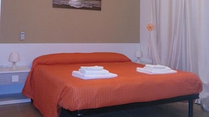 A bedroom with a bed, a nightstand, a lamp, a painting, and a curtain. - BB Il Quadrifoglio (San Vito dei Normanni)