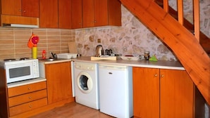 Une cuisine compacte avec des meubles en bois, un four à micro-ondes, un lave-linge et un escalier en bois.