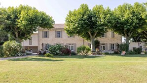 A stone building with a garden in front, featuring a lawn, trees, and outdoor seating.