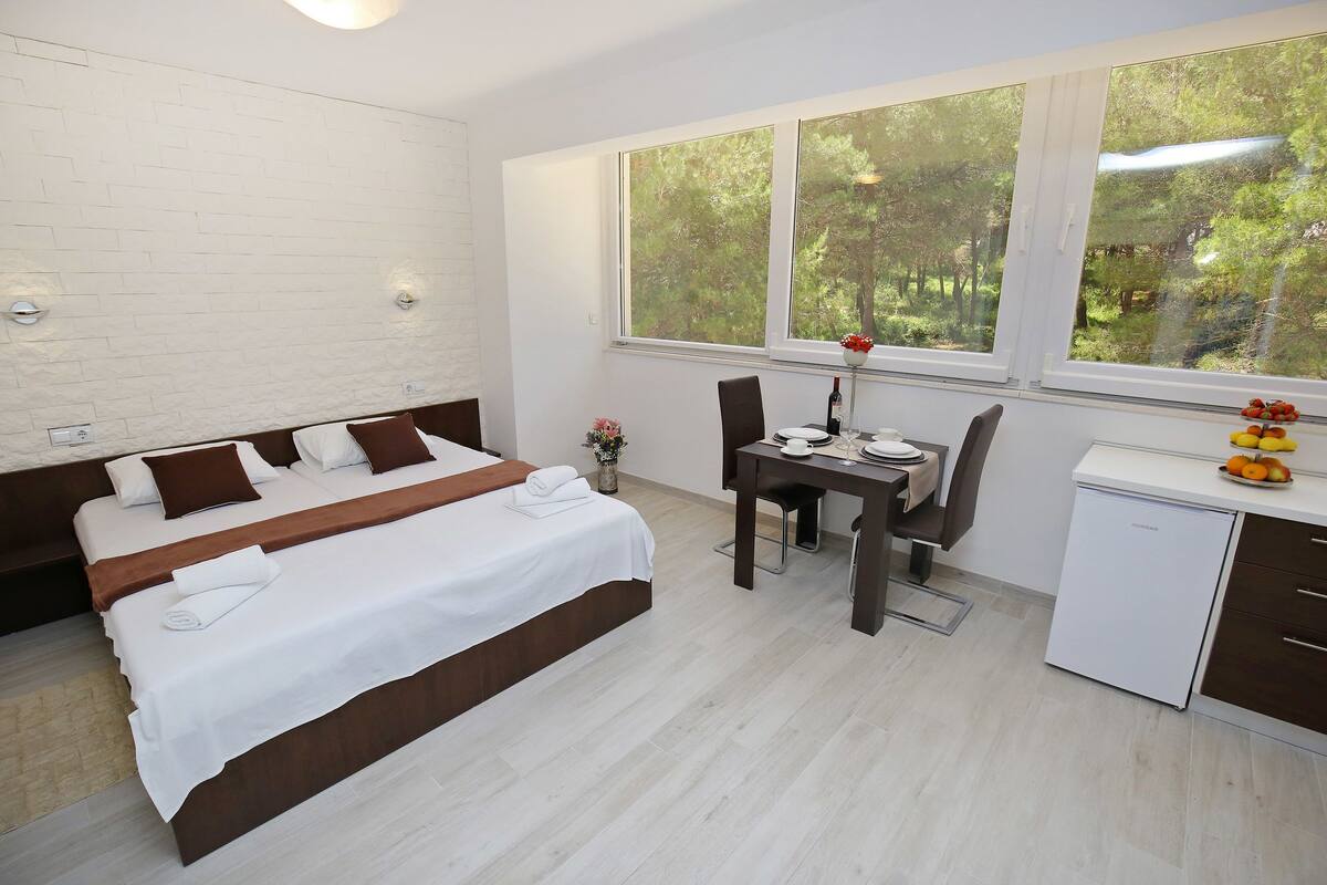 A bedroom with a bed, a desk, and a small refrigerator.