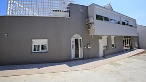 A modern building with a flat roof, large windows, and a covered entrance. - Deluxe Mkc Apartments (Zadar)