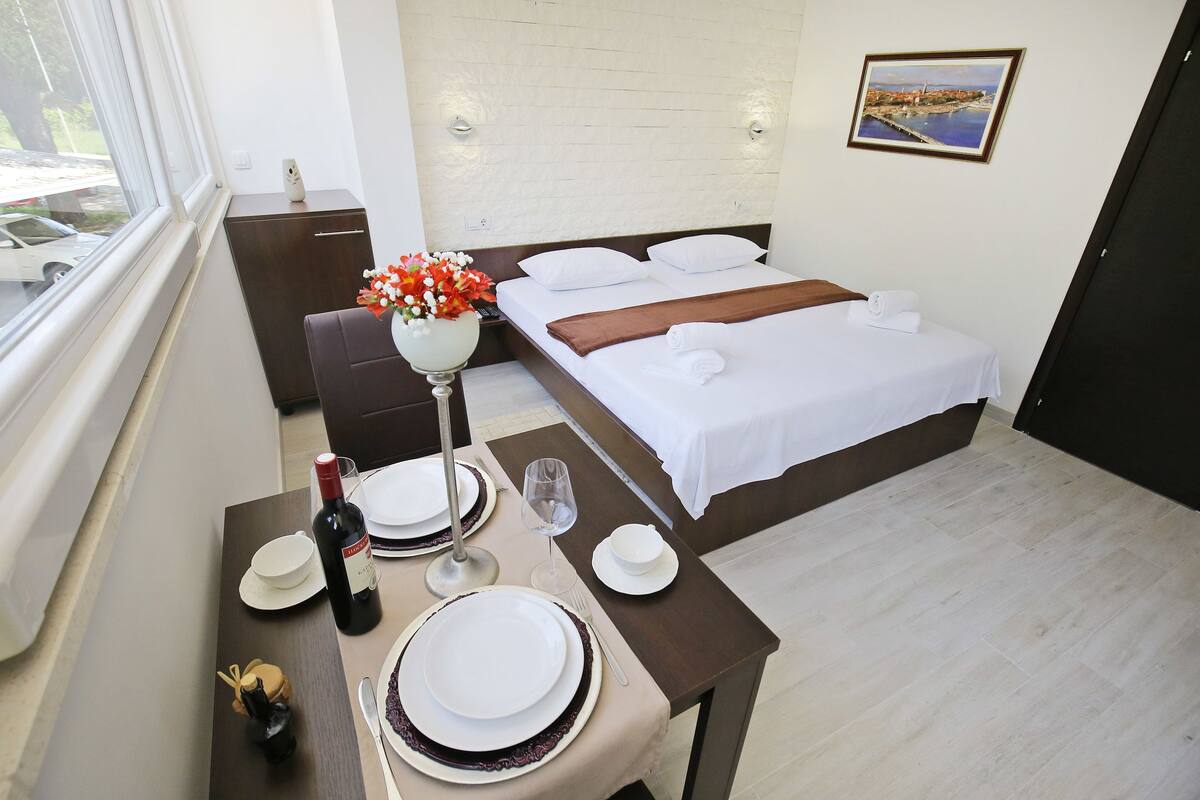 A neatly arranged hotel room with a bed, bedside table, and a view of the outside.