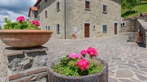 A stone building with a courtyard, a large flower pot, and potted plants.