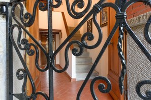 Eine Treppe mit schwarzem schmiedeeisernen Geländer, Holzwänden und einem gefliesten Boden.