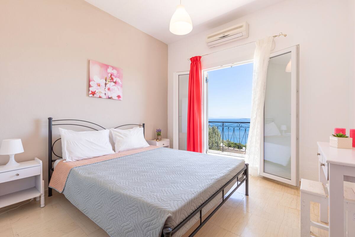 Une chambre à coucher comprenant un lit, une table de chevet, une commode et une fenêtre donnant sur un beau paysage.