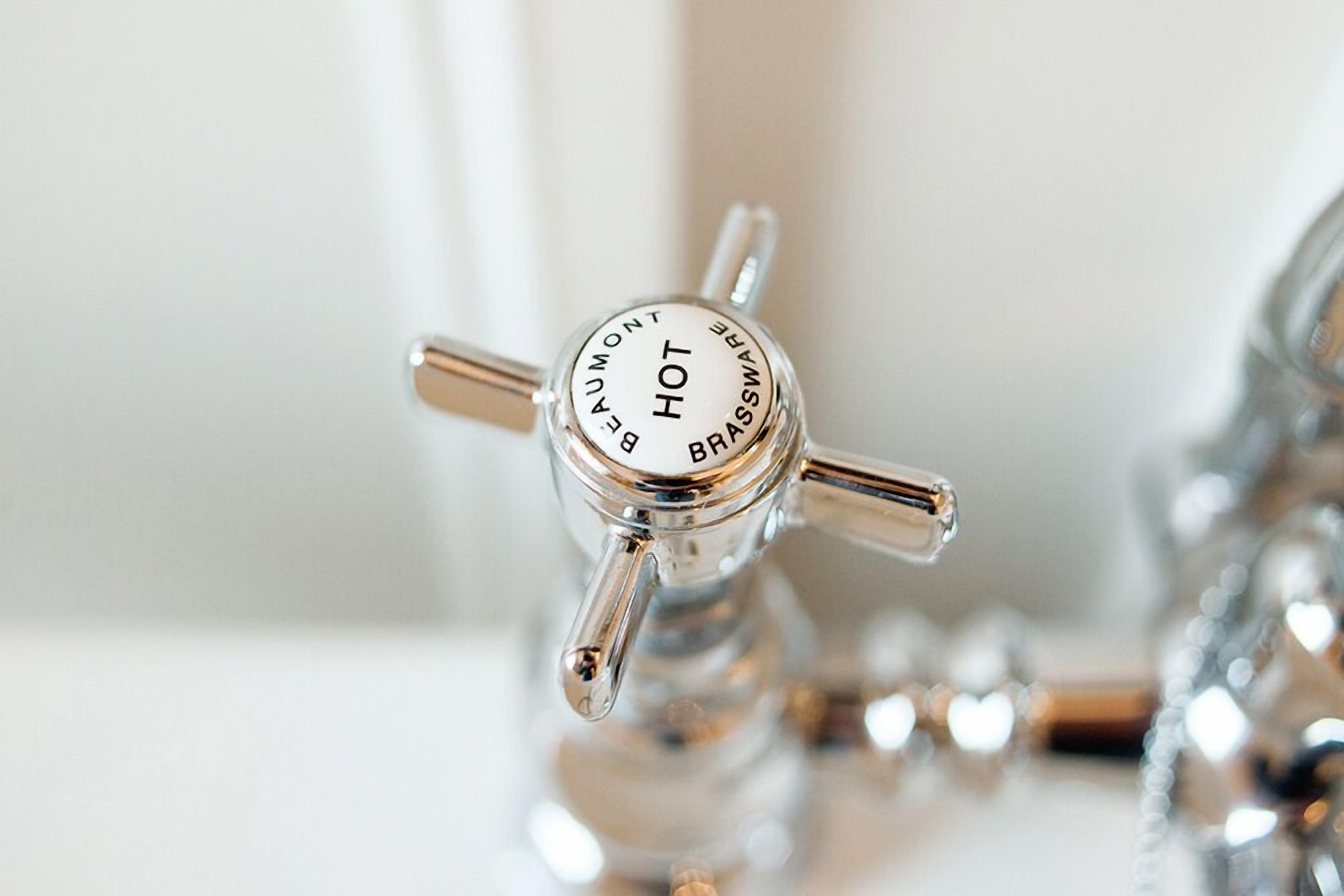 A close-up of a brass hot water tap with the words "HOT" and "BRASS" visible.