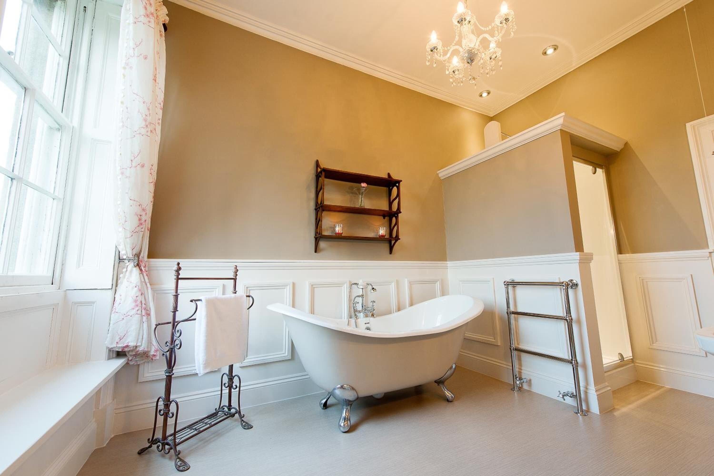 A bathroom with a freestanding bathtub, a vanity with a mirror, and a chandelier.