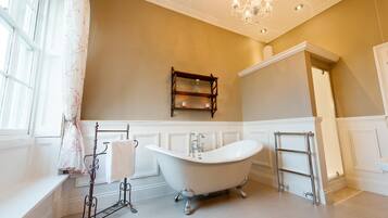 A bathroom with a freestanding bathtub, a vanity with a mirror, and a chandelier.