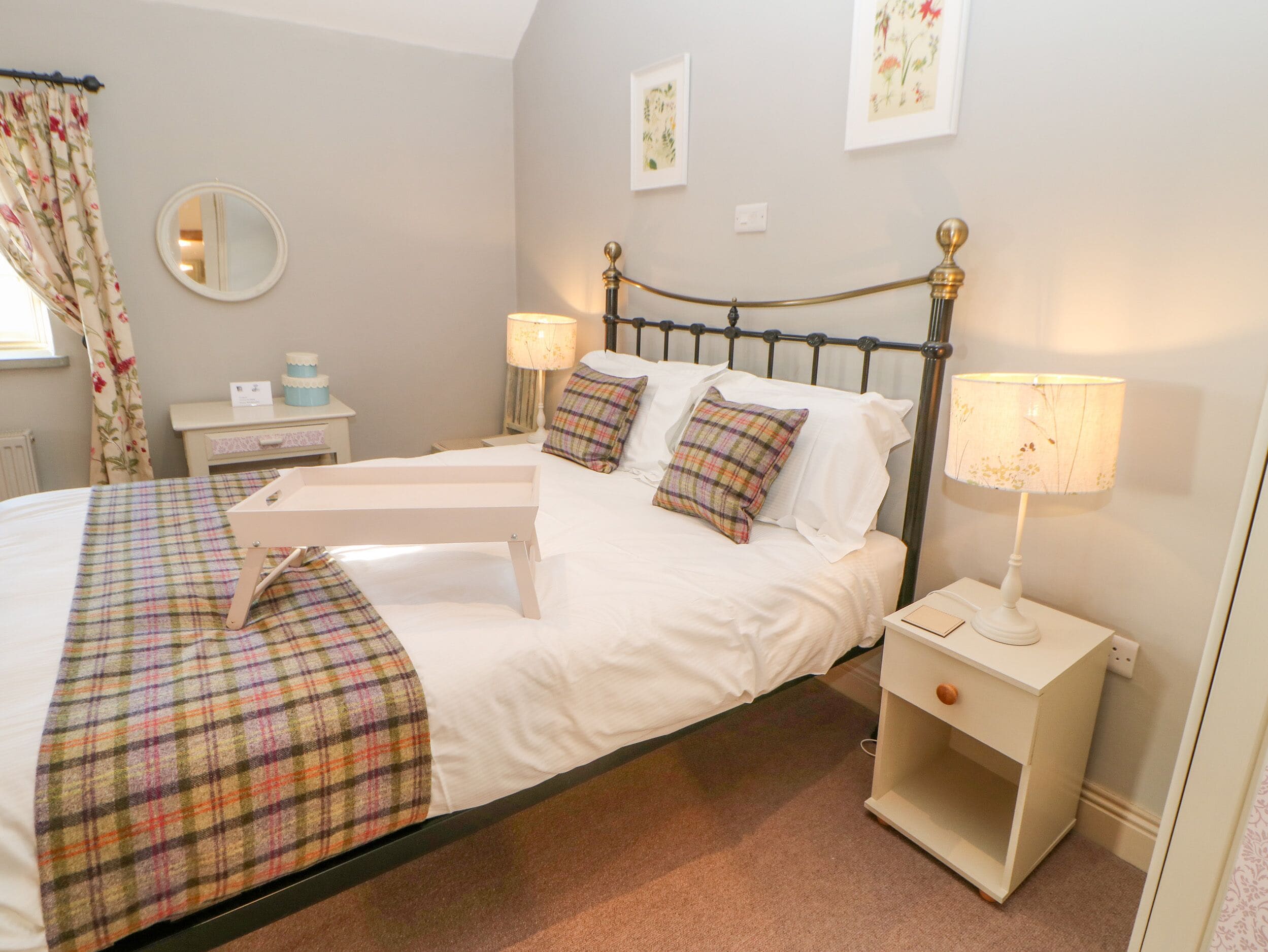 A neatly made bed with a plaid bedspread, two bedside lamps, and a nightstand with a lamp.