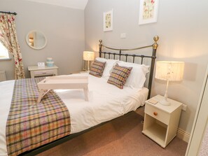 A neatly made bed with a plaid bedspread, two bedside lamps, and a nightstand with a lamp. - The Stable, Sedbury Park Farm (Richmond)