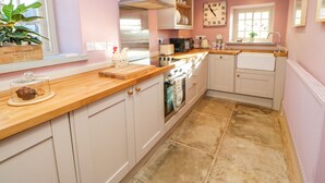 A kitchen with white cabinets, a wooden countertop, a stainless steel range hood, a microwave, a kettle, and a clock on the wall. - The Stable, Sedbury Park Farm (Richmond)