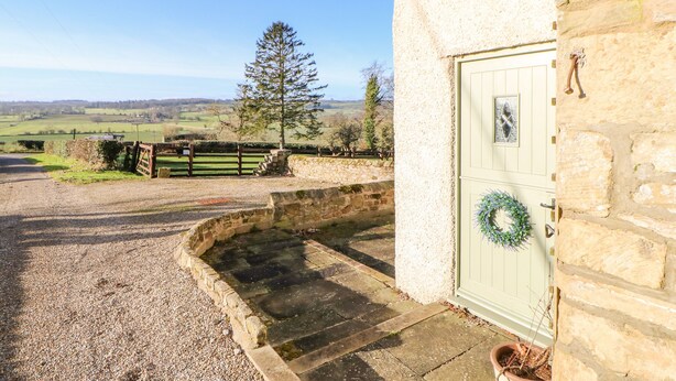 A stone building with a green door, a wreath, and a view of a rural landscape. - The Stable, Sedbury Park Farm (Richmond)