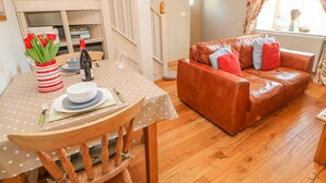 A dining area with a polka dot tablecloth, a wooden chair, a brown leather sofa, and a vase of red tulips. - The Stable, Sedbury Park Farm (Richmond)