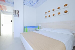 Un dormitorio con una cama, una mesita de noche y una estantería de pared decorada con objetos.