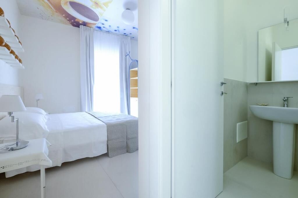 Un dormitorio con cama, mesita de noche y ventana con cortinas.