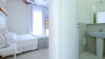 Un dormitorio con cama, mesita de noche y ventana con cortinas.