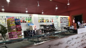 A bar area with a glass counter, shelves of liquor bottles, and a coffee machine. - La Staffa B&B Ristorante (Ugento)
