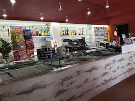 A bar area with a glass counter, shelves of liquor bottles, and a coffee machine.
