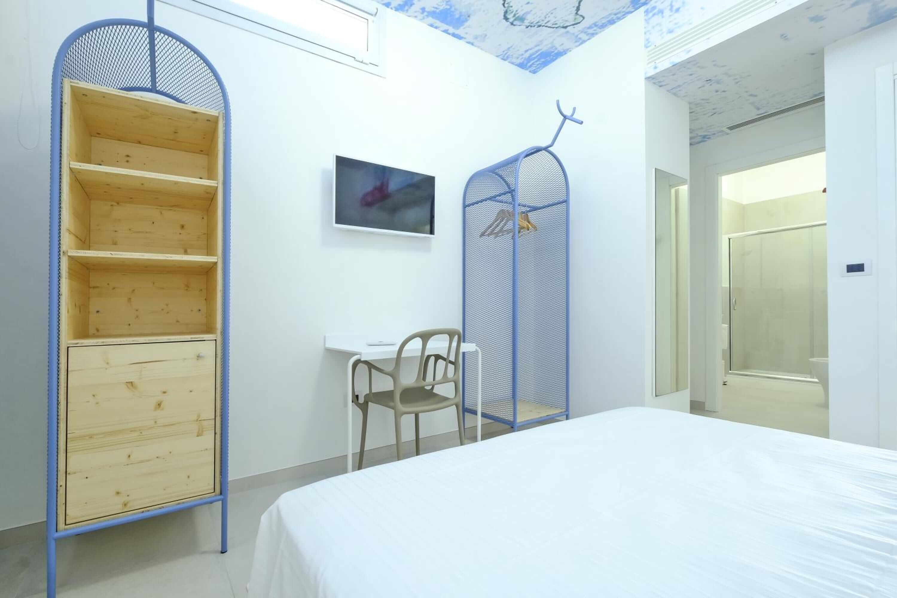 A bedroom with a bed, a desk, a chair, and a wardrobe.