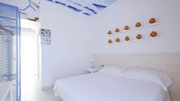 A bedroom with a large bed, a nightstand, and a wall-mounted shelf with decorative items.