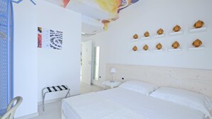 A hotel room with a large bed, a small table, a chair, and a wall with decorative items. - La Staffa B&B Ristorante (Ugento)