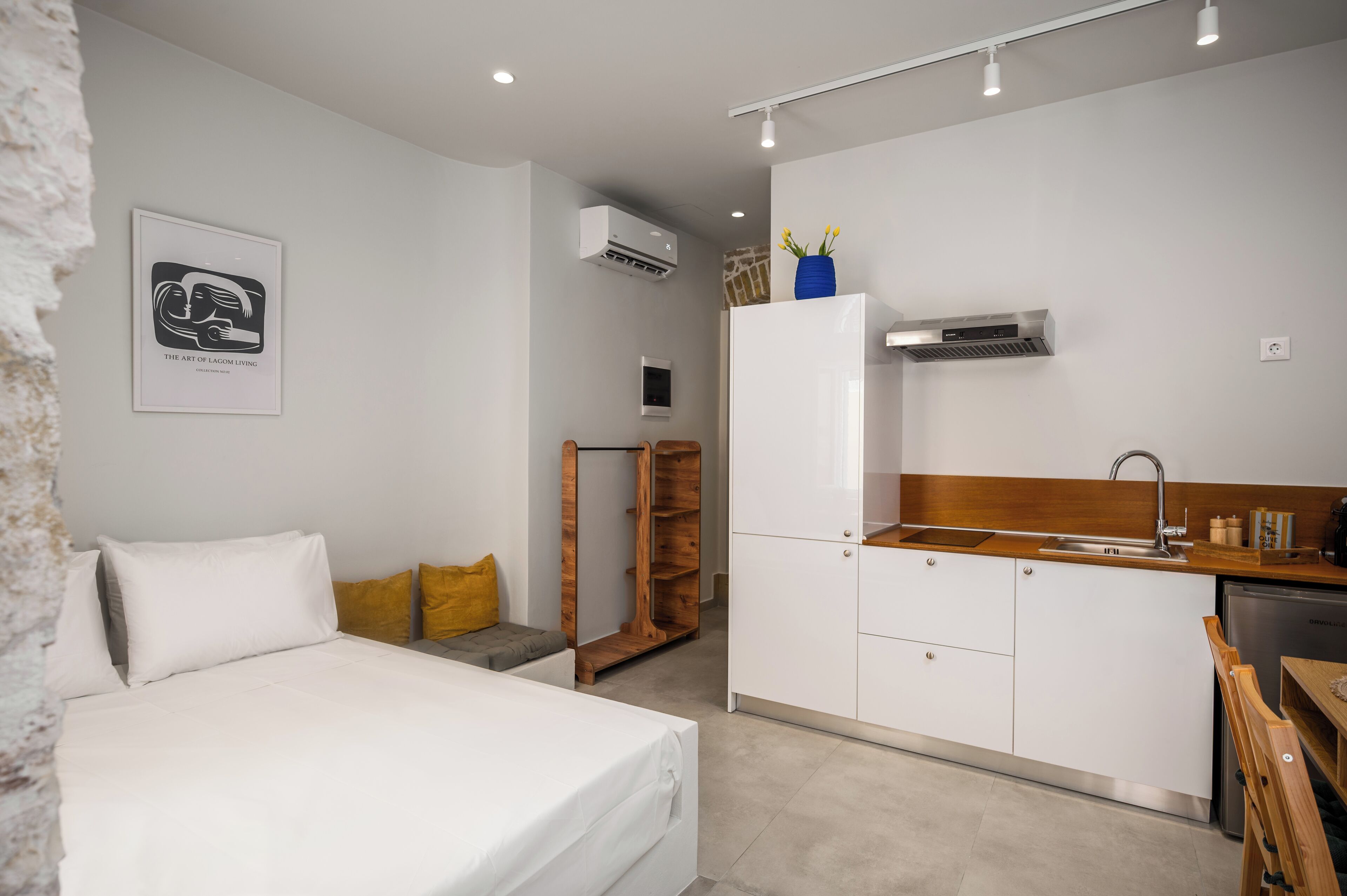 Ett modernt och kompakt hotellrum med en säng, ett litet pentry och en garderob i trä.