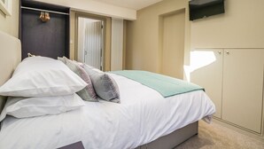 A bedroom with a bed, a TV mounted on the wall, and a wardrobe. - Providence Cottage (York)