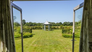 A view through open doors to a well-maintained garden with a gazebo. - Providence Cottage (York)