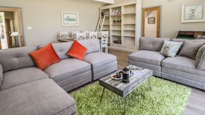 A modern living room with grey sofas, a coffee table, and a bookshelf. - Providence Cottage (York)