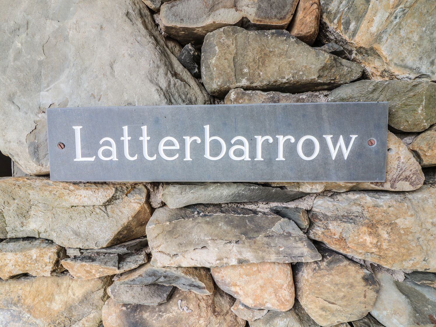Un muro di pietra con un cartello che riporta la scritta 'Latterbarrow'.
