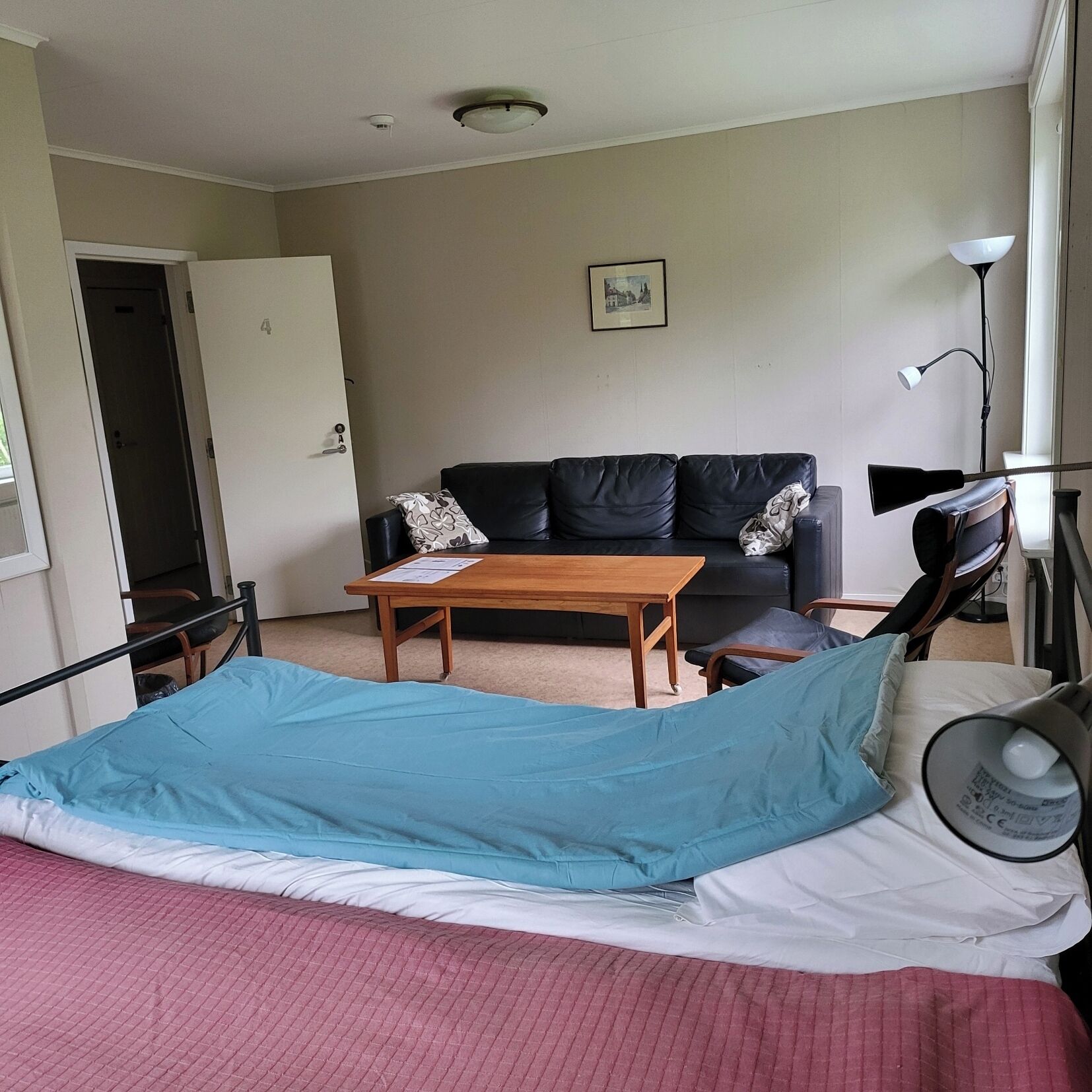 Quarto com uma cama, uma mesa de madeira, um sofá preto e um abajur.