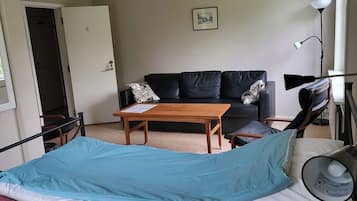 Quarto com uma cama, uma mesa de madeira, um sofá preto e um abajur.