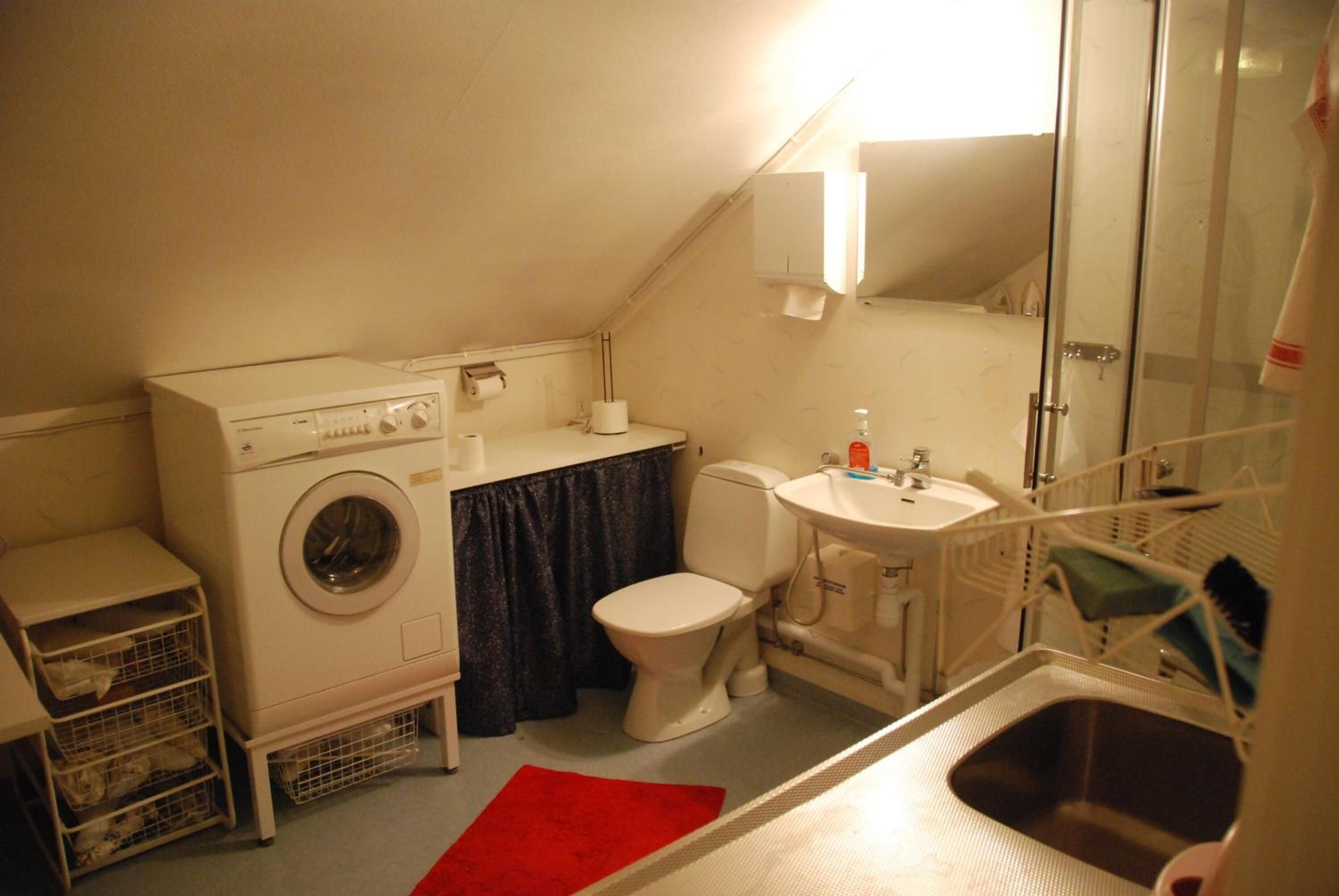 Ein kleines Badezimmer mit Waschmaschine, Toilette, Waschbecken und Duschbereich.