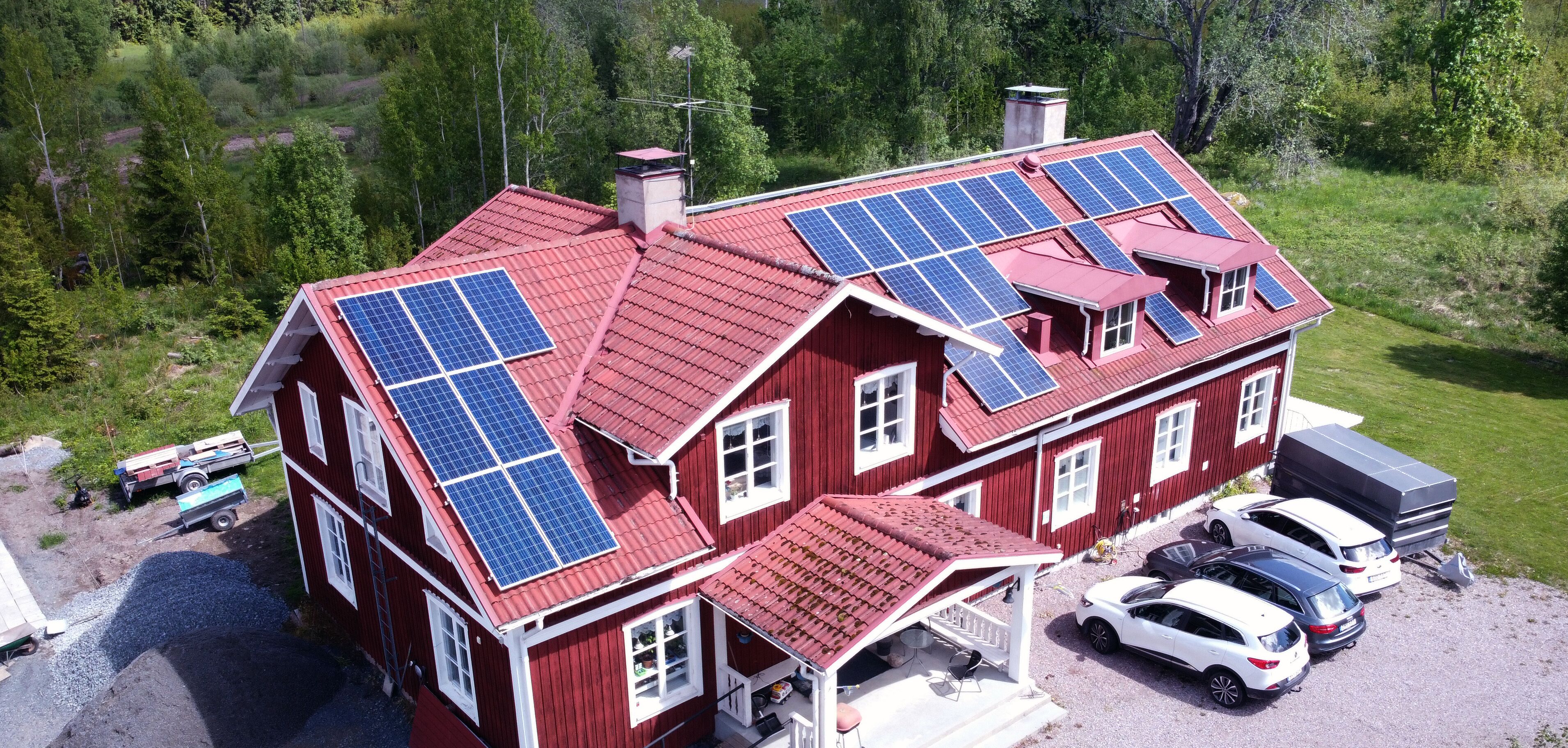 A red house with solar panels on the roof and a covered porch.