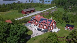 A red barn with solar panels, a driveway, and a small house with a red roof.