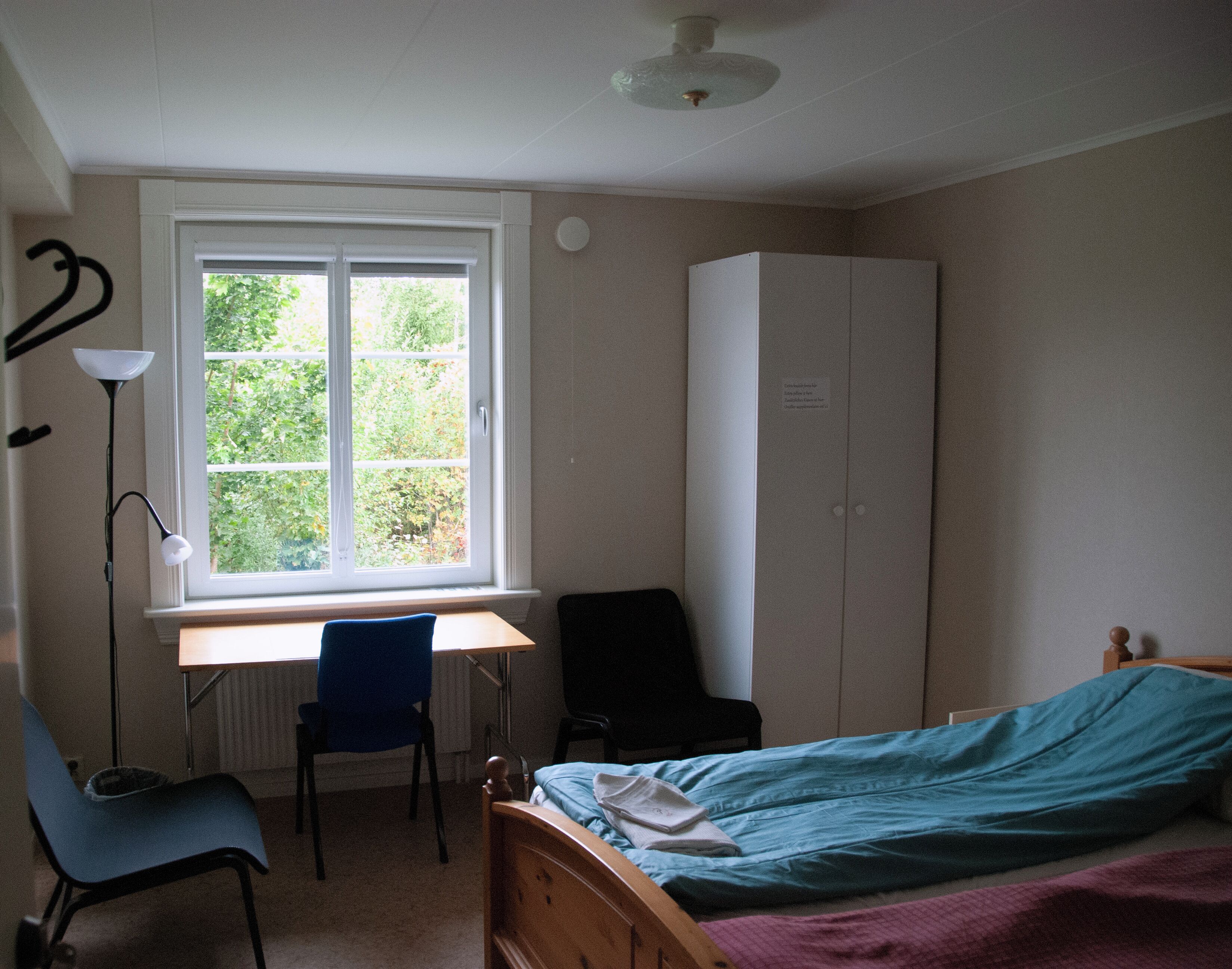 A bedroom with a single bed, a desk, and a wardrobe.