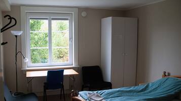 A bedroom with a single bed, a desk, and a wardrobe.
