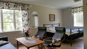 A bedroom with a bed, two chairs, a table, and a window.