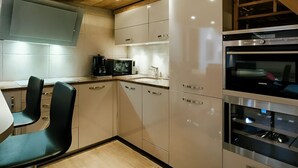 Una cocina moderna con vigas de madera en el techo, electrodomésticos de acero inoxidable y un comedor con sillas.