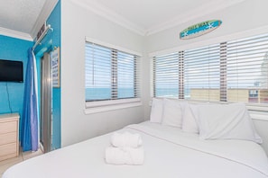 A hotel room with a bed, a window with blinds, a towel on the bed, and a sign above the window.